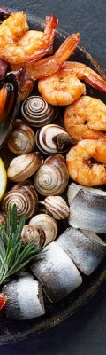 Seafood charcuterie board with shrimp, oysters, fish and octopus. Top view, close up Seafood charcuterie platter board with shrimp, oysters, fish and octopus on black background. Top view, close up